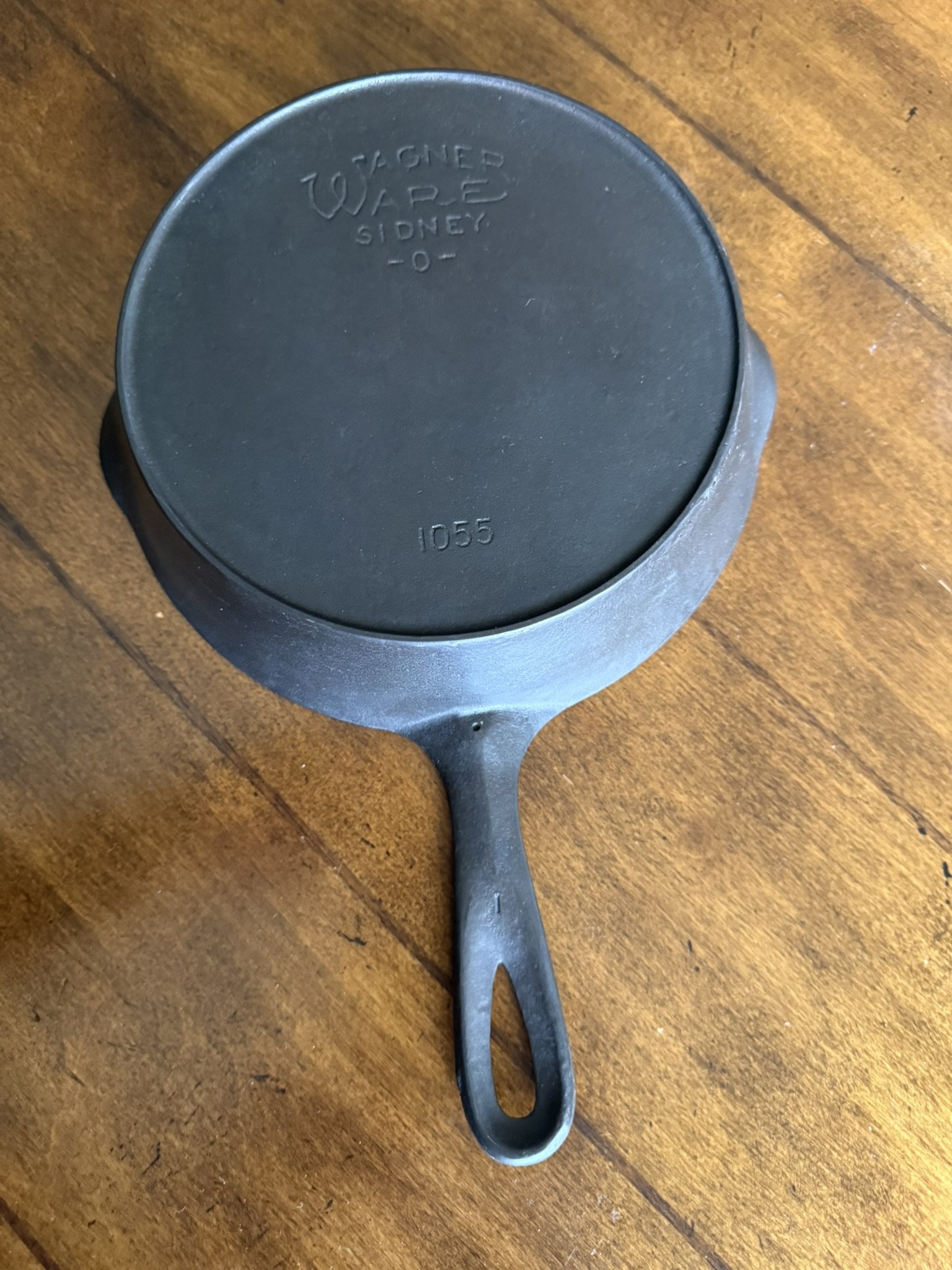 Cast iron skillet with a long handle, resting on a wooden surface.