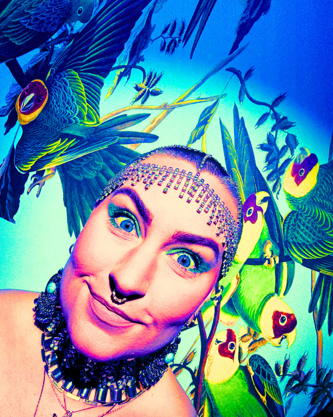 A person with vibrant makeup and jewelry taking a selfie in front of a colorful mural of parrots and tropical plants.