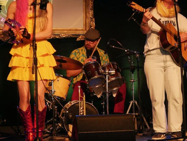 Musicians performing live on stage with drums and guitars.