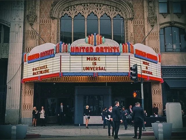 Marquee sign for United Artists Theater with the message "Music is Universal" and people walking outside.
