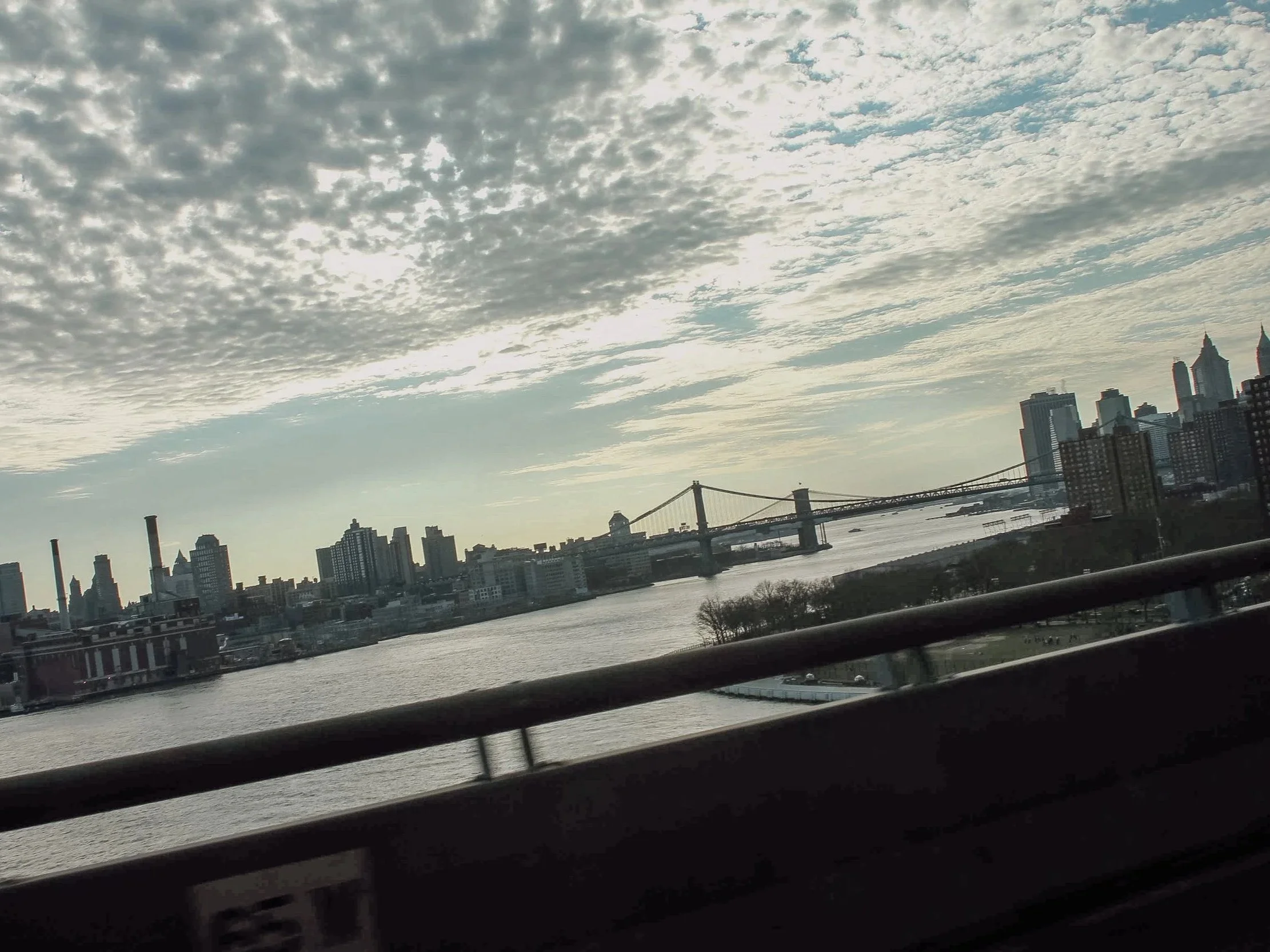 City skyline of Manhattan with the Brooklyn Bridge over the East River on a cloudy day.