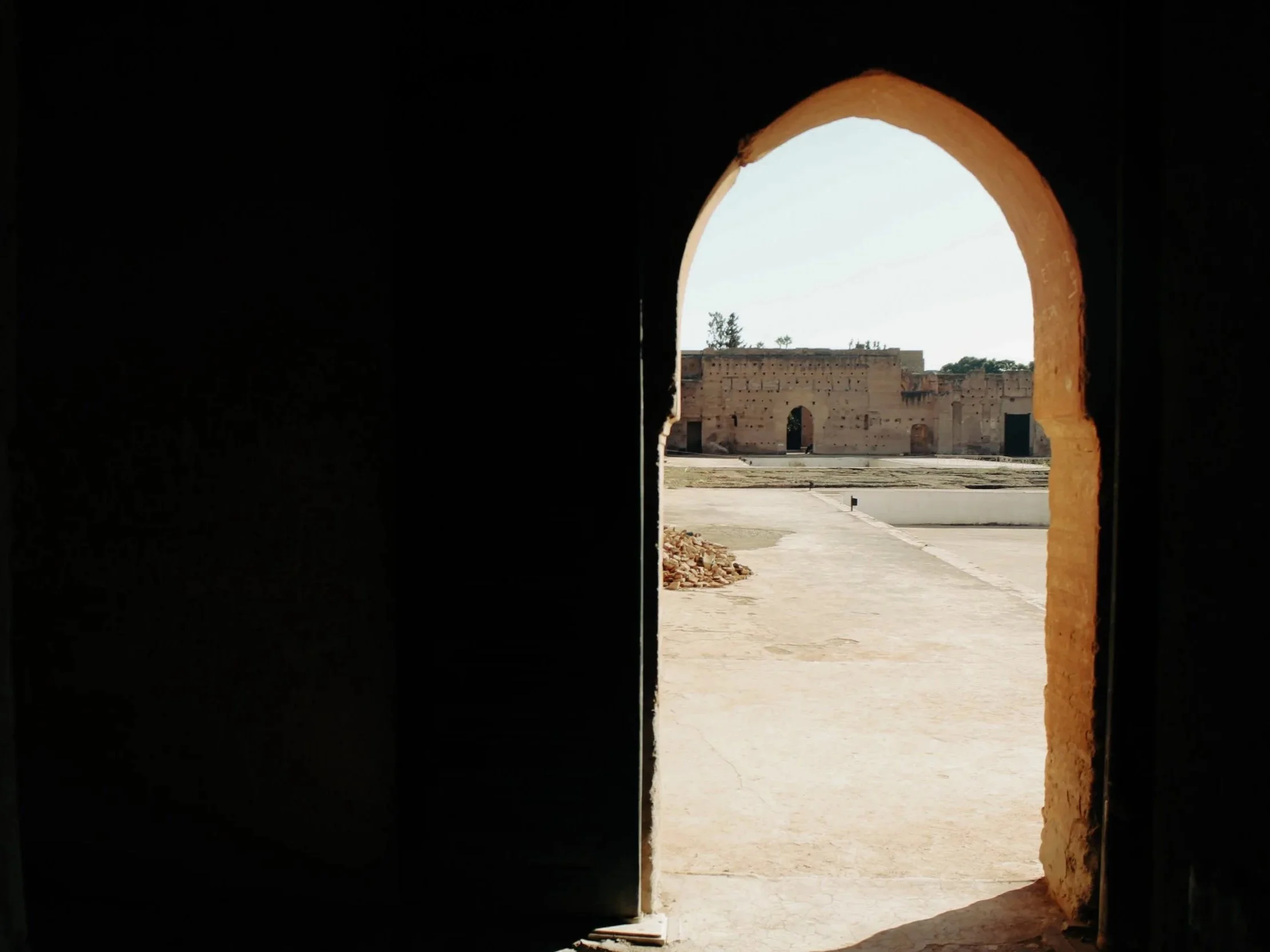 View through an arched doorway showing ancient ruins outside in a desert-like area.