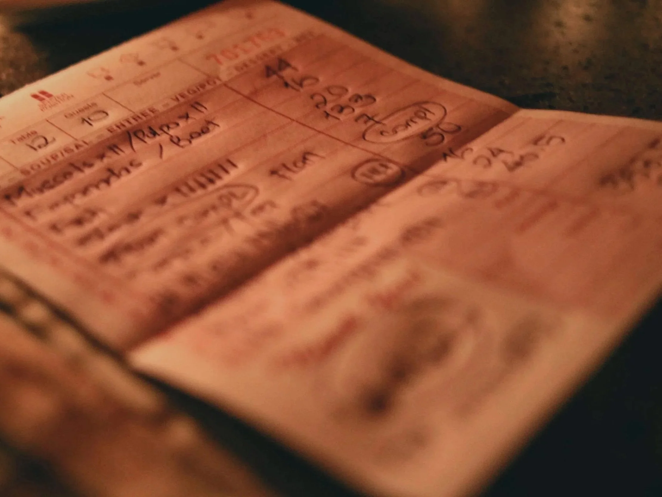 Close-up of a paper ticket or document with handwritten notes and printed text, slightly out of focus, on a dark surface.
