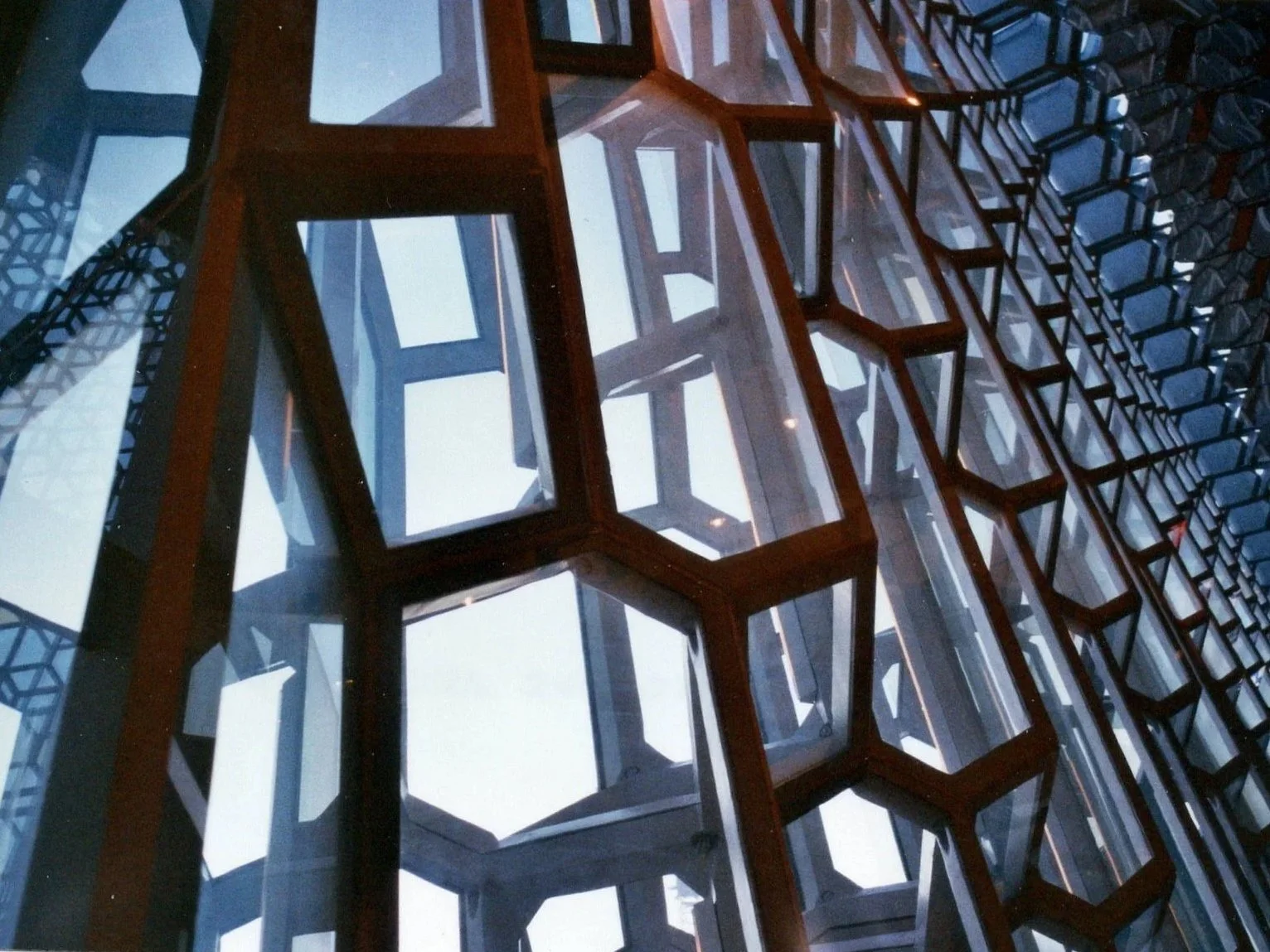 Close-up view of a modern building facade with hexagonal window frames and glass panes creating geometric patterns and reflections.