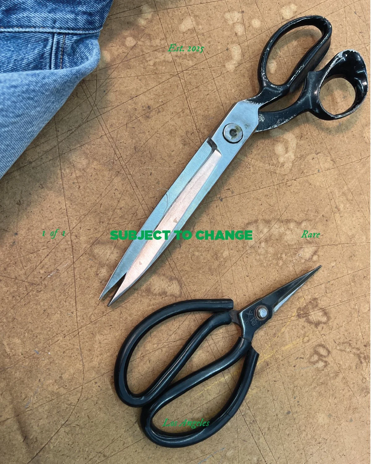 A pair of black scissors with a curved handle and metal blades, and a pair of silver-threaded scissors with a straight handle and pointed blades, on a wooden surface with green text overlay reading 'Est. 2025', 'SUBJECT TO CHANGE', '1 of 1', 'Rare', 