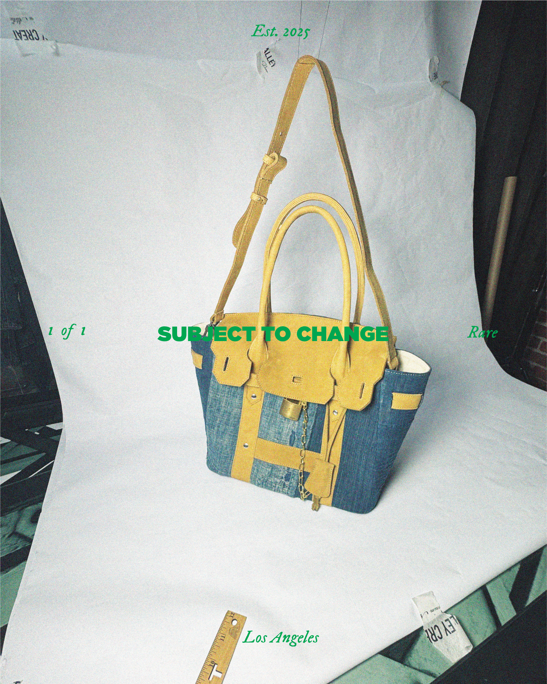 A multicolored handbag with yellow handles and straps, featuring mixed denim and yellow leather material, resting on a white surface with a ruler and some paper in the background. Text overlays include "Est. 2025" at the top, "1 of 1" on the left, "R
