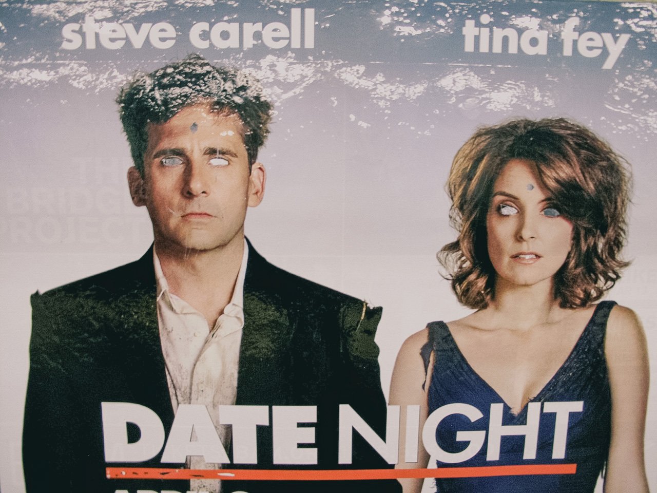 A promotional poster for the movie 'Date Night' featuring actors Steve Carell and Tina Fey. Steve Carell has messy hair and is looking upward with his eyes edited to be blank. Tina Fey has curly, shoulder-length hair and is looking to the side with h