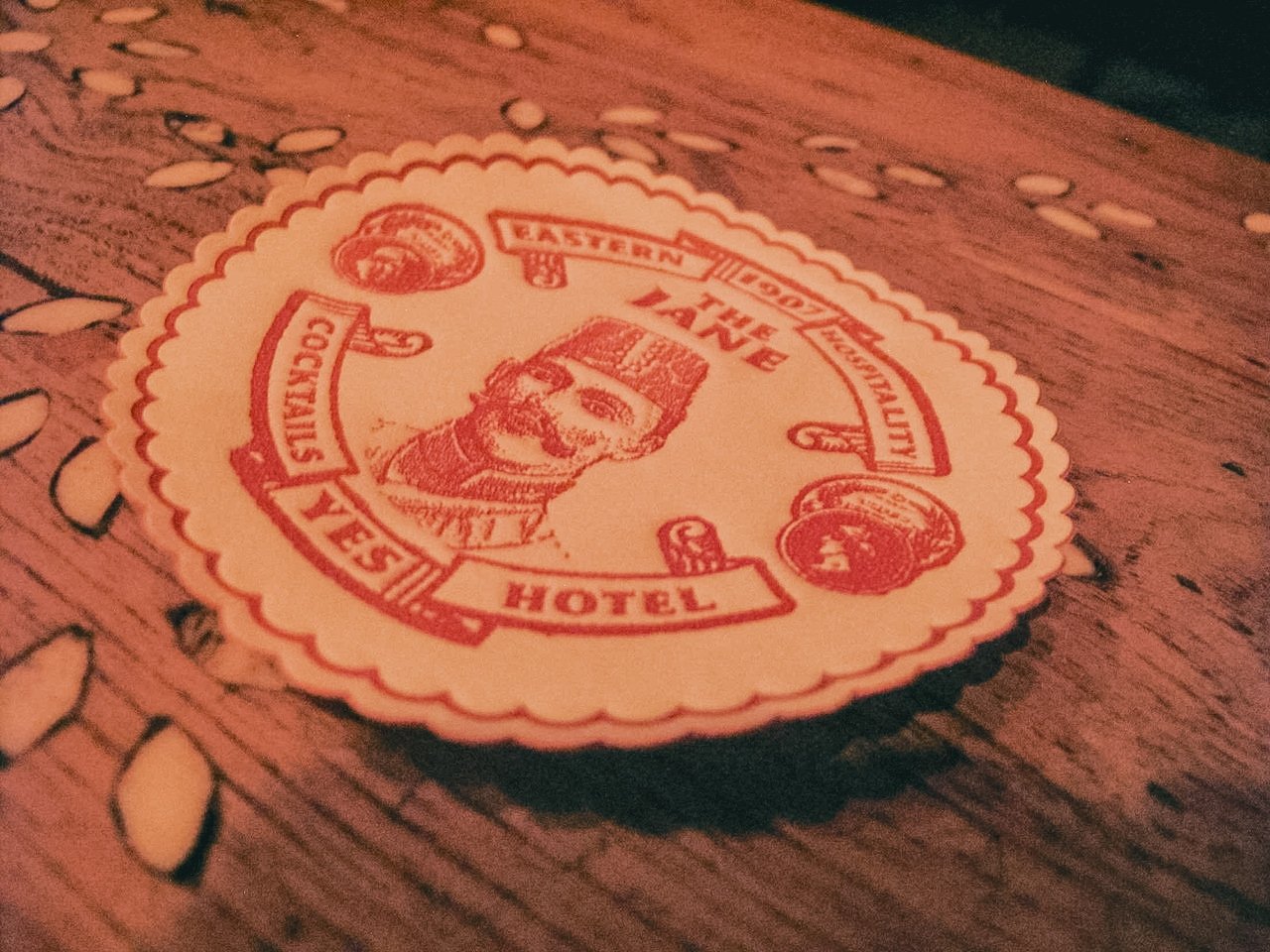 A round sticker with a red border and vintage design, featuring a portrait of a man. The sticker has text indicating it's from the Eastern Hotel, with words like 'Authentic,' 'East Coast,' and 'Lighthouse' around the border. The sticker is placed on 