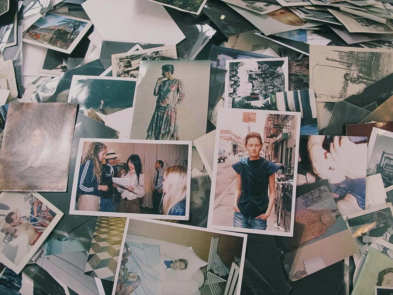 A collection of various printed photographs scattered on a surface, including portraits, candid shots, and scenes from different locations and events.