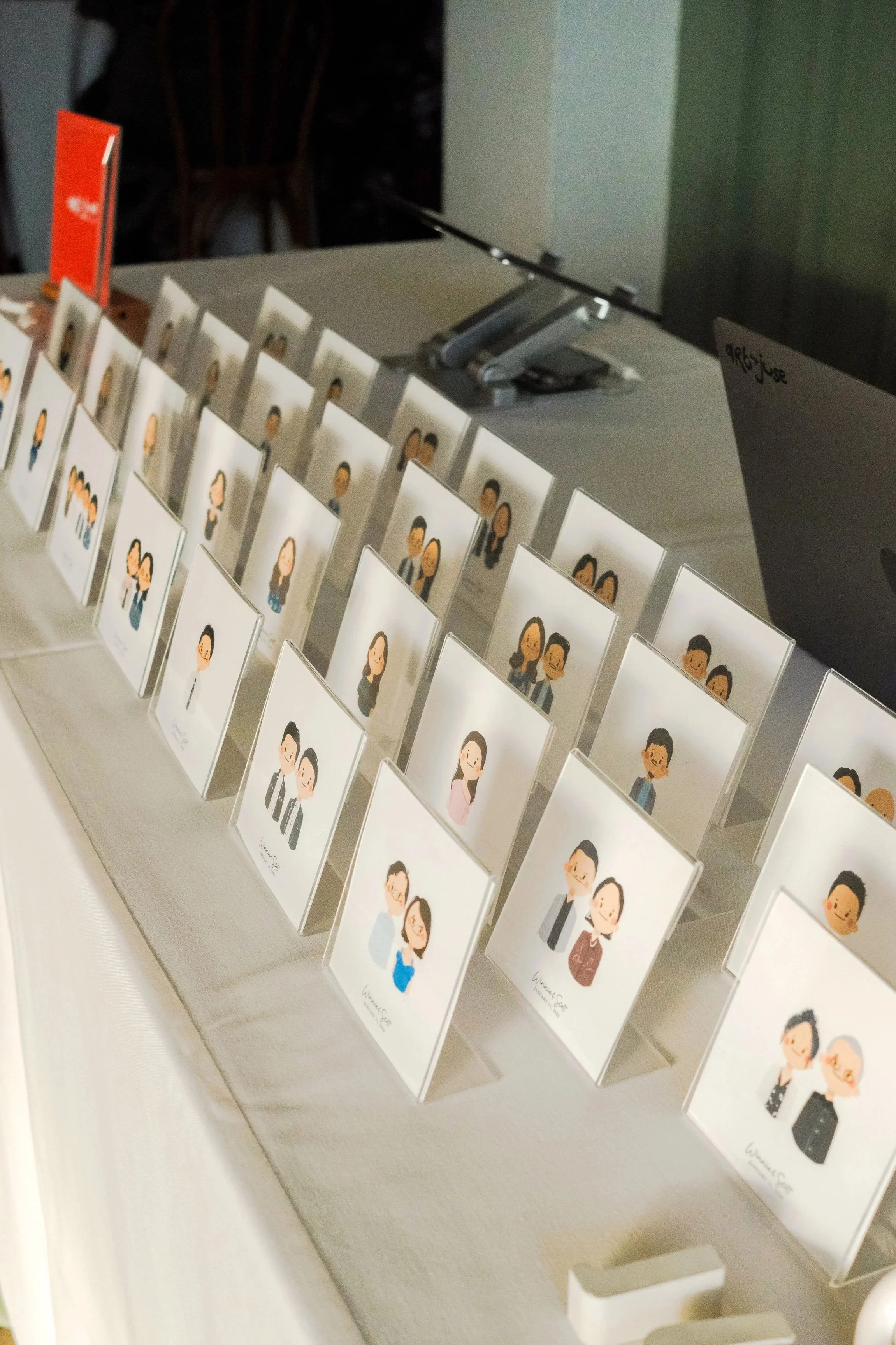 Display of illustrated name cards featuring diverse cartoon characters, arranged on a table at an event.