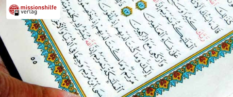 Nahaufnahme eines Korans mit arabischem Text und bunten Ornamenten am Rand.