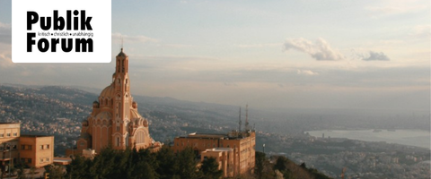 Blick auf eine Stadt im Libanon mit einer markanten katholischen Kirche auf einem Hügel im Vordergrund und einem Fluss im Hintergrund