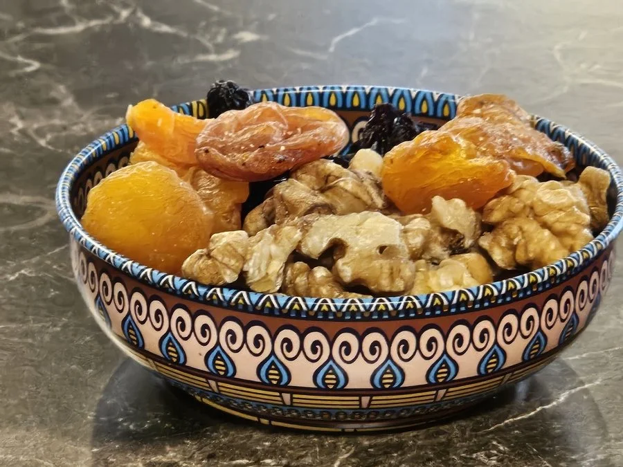 Schüssel mit Trockenfrüchten, einschließlich Aprikosen, Feigen, Rosinen und Walnüssen, auf einem dunklen Marmor Tisch.