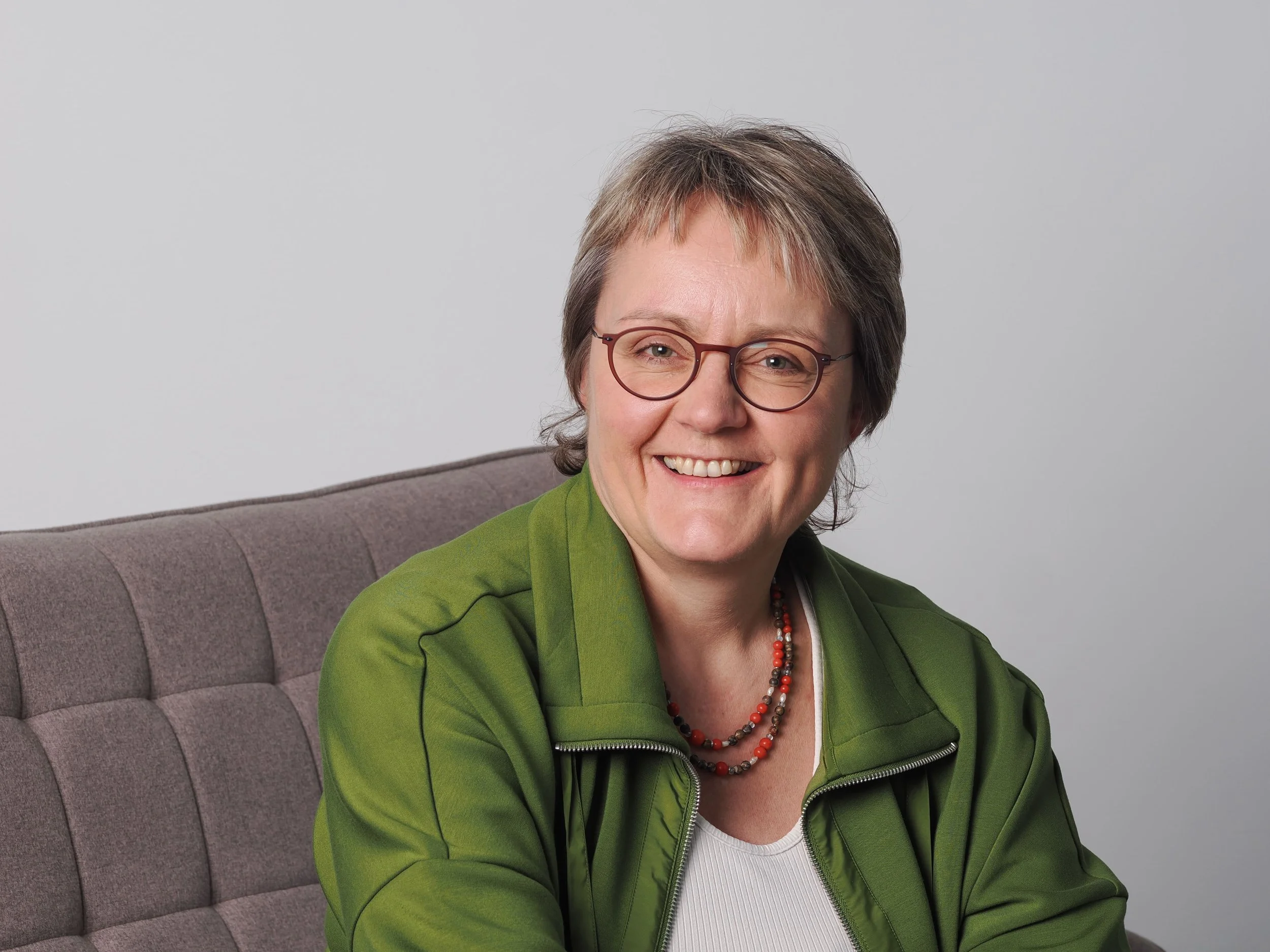 Politologin und Religionswissenschaftlerin Katja Dorothea Buck sitzt lächelnd auf einer Couch