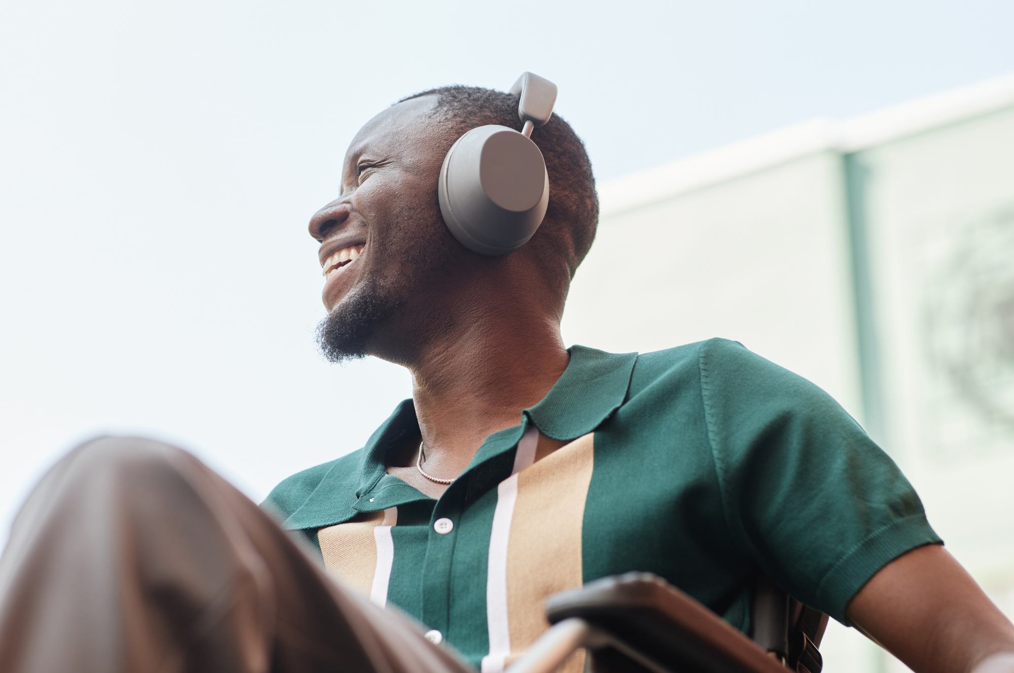 Smiling man wearing headphones outdoors, looking happy and relaxed.