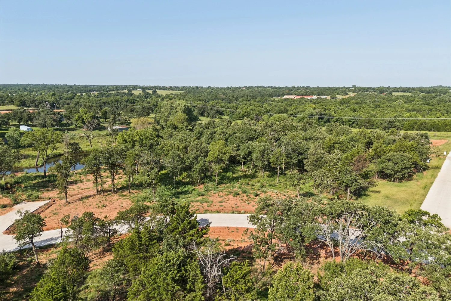 Aerial of wooded acreage with a clearing and the land around it