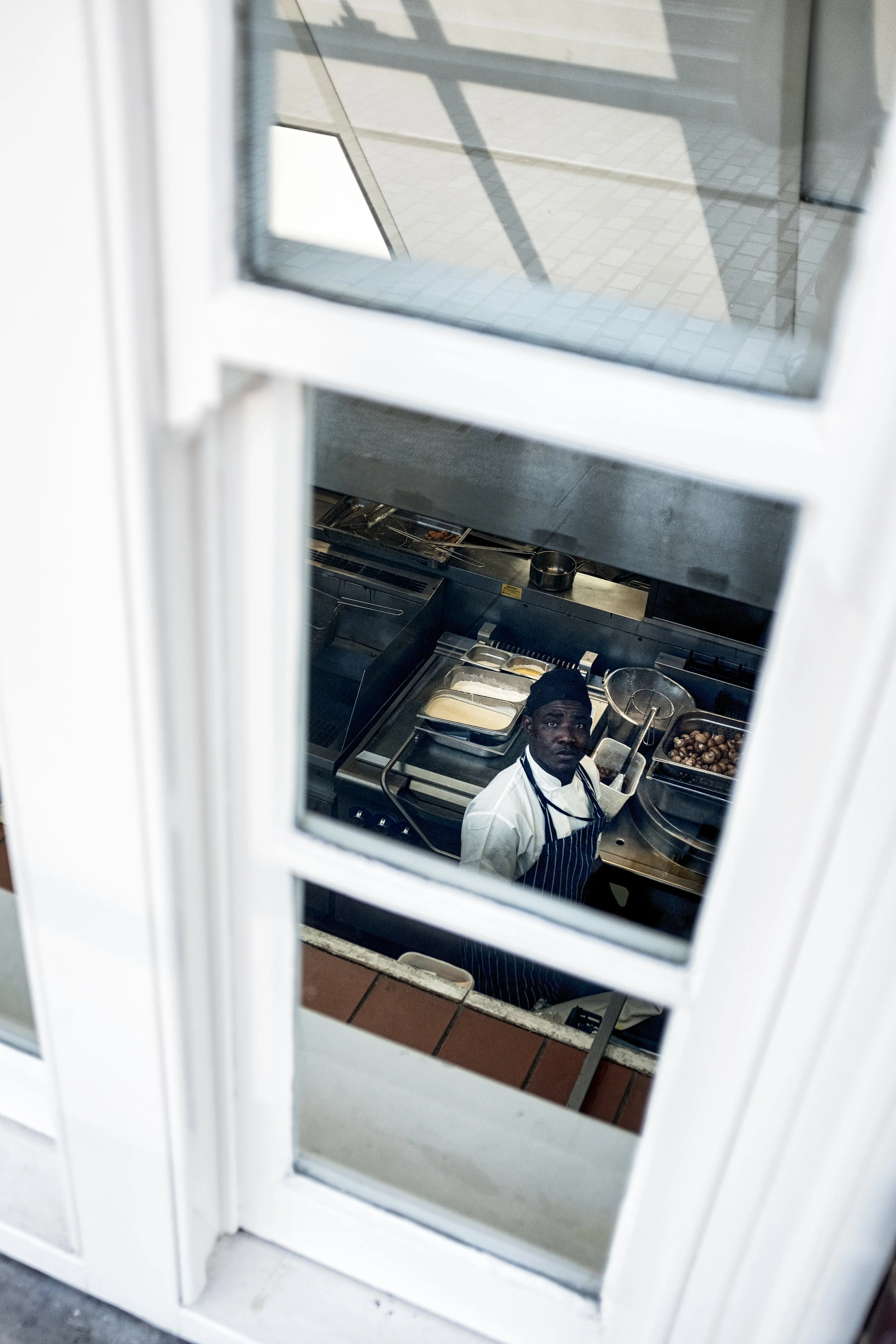A chef looking up through a window into a restaurant kitchen.