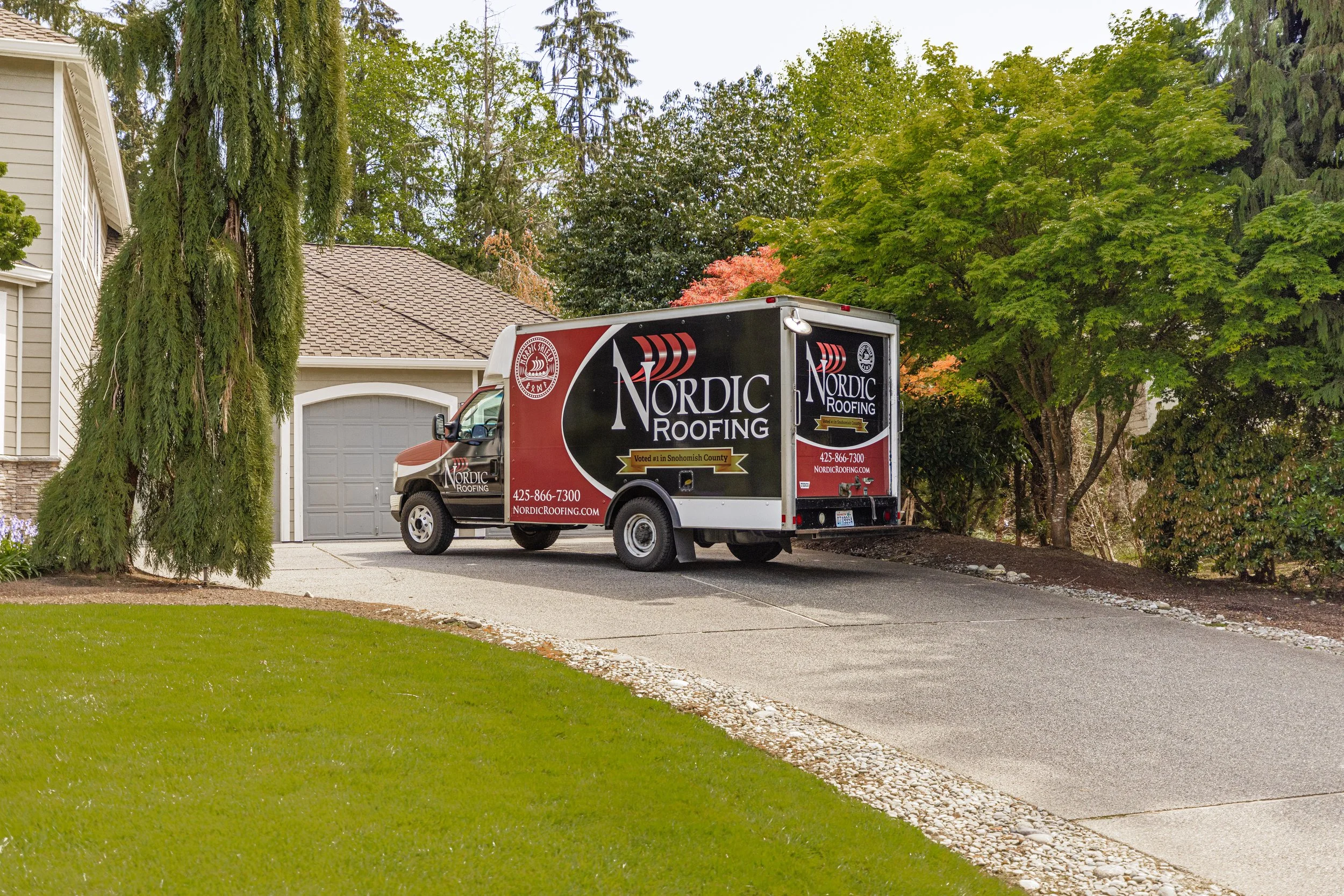Long paved Driveway with a company Nordic Roofing boxtruck and garage