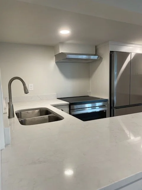 Modern downstairs kitchen remodel in Blackmans Lake Neighborhood of Snohomish, WA. Featuring stainless steel appliances, stainless steel range hood, and a double sink with a white marble countertop. A custom design-build by Nordic Home Solutions