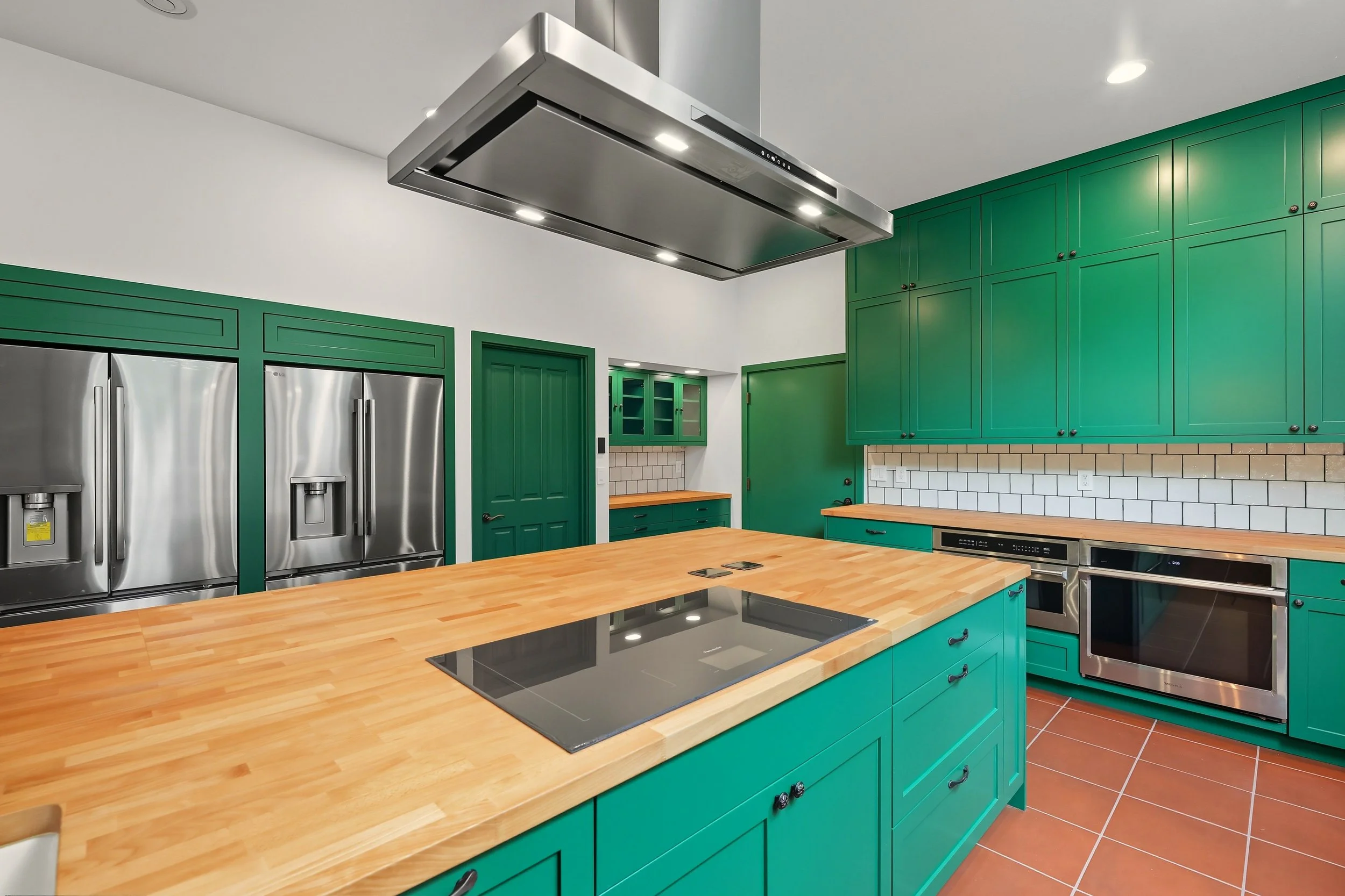 Modern Chef style kitchen custom designed with green cabinets and  butcher block countertop island with built in electric stovetop