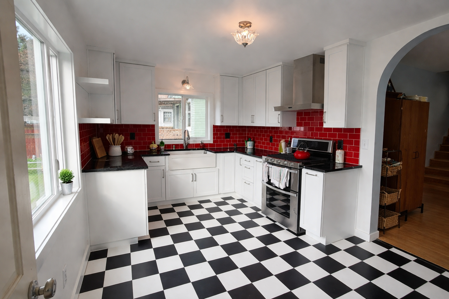 A historic 1950's Kitchen remodel in Snohomish, WA designed and built by Nordic Home Solutions. Showcasing a 50's theme kitchen with checkered black and white flooring, custom red tile backsplash, white cabinets, and black marble countertops.