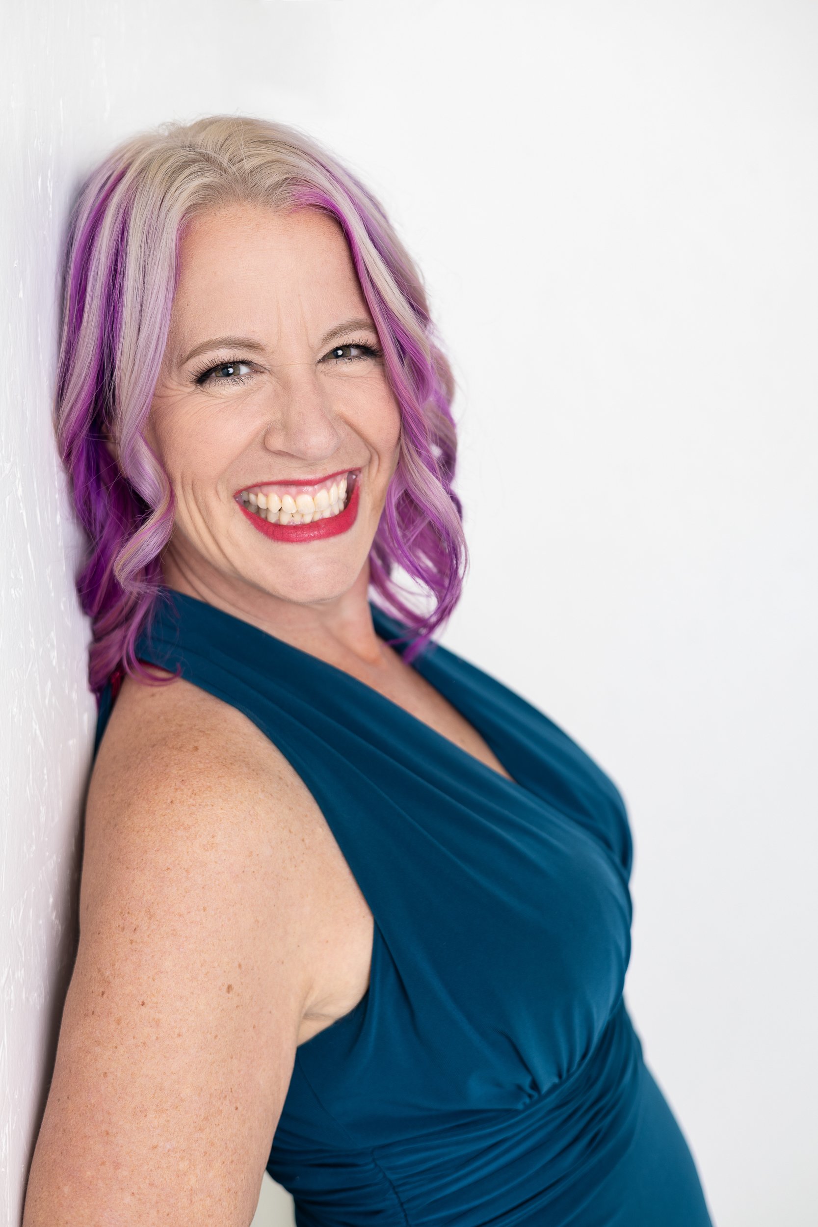 Elegant mature woman in red dress with silver jewelry, smiling during a studio portrait session with Charlotte Harloff Portraits in Colorado Springs