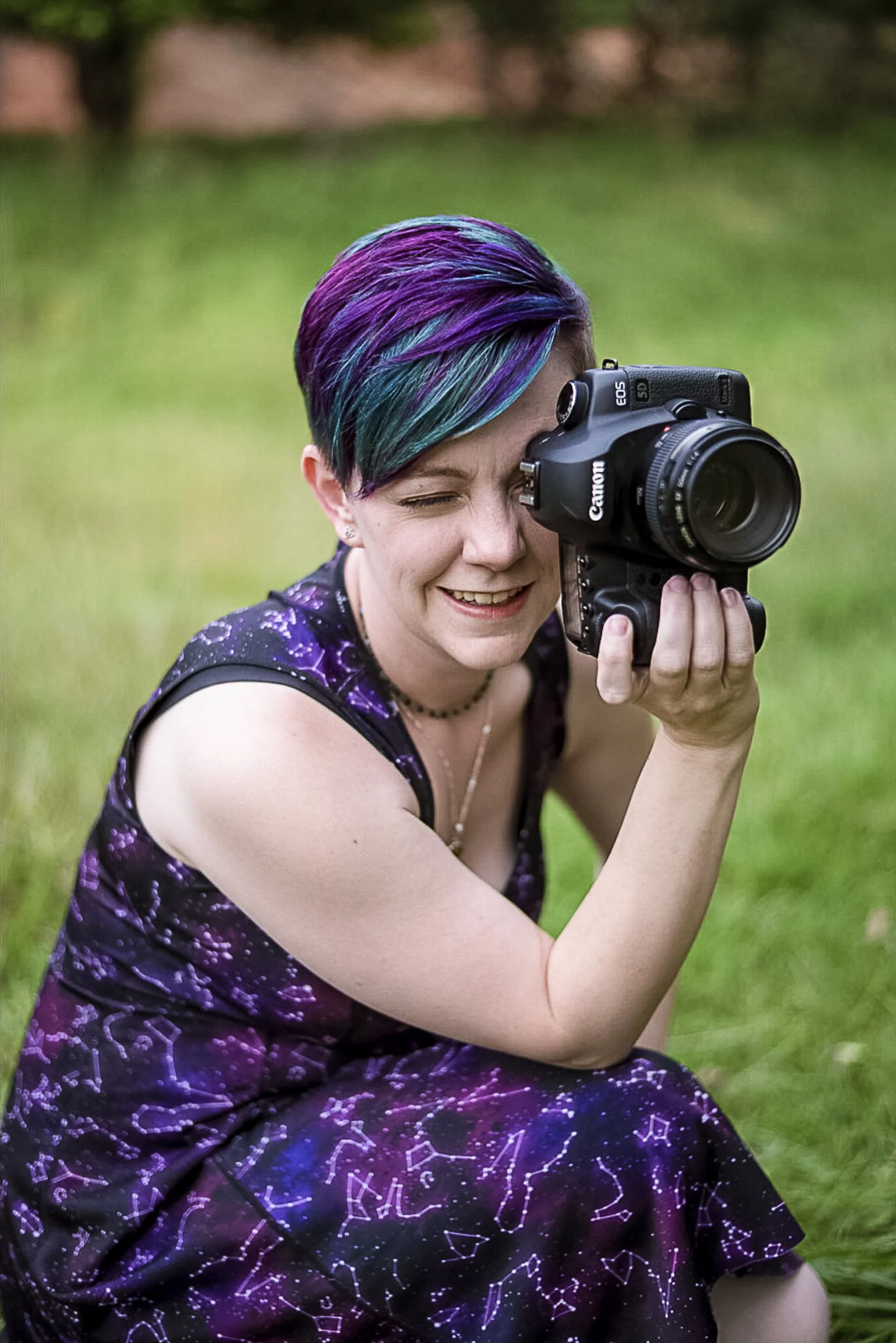 Charlotte Harloff photographing outdoors with a Canon camera, smiling with short multicolored hair — behind the scenes of a stress-free, guided portrait experience