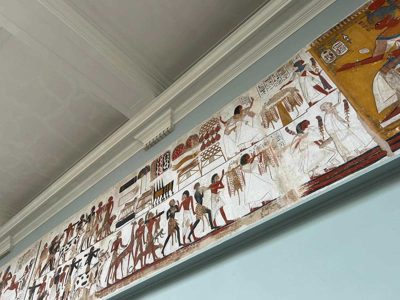 Ancient Egyptian painted papyrus scroll depicting figures in traditional attire performing rituals and daily activities.