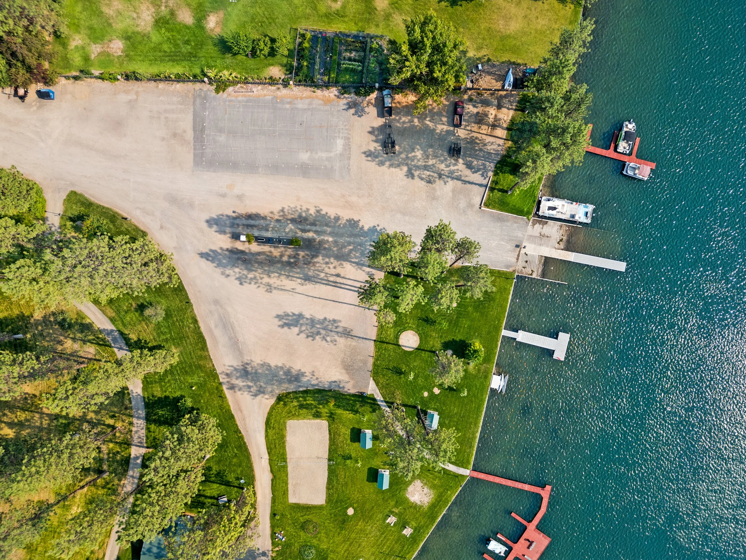 Aerial view of a lakeside park showing greenery, parking lot, boat docks, and boats on the water.