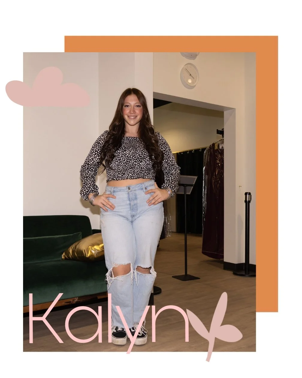 A young woman with long brown hair smiling in a casual outfit of a black and white patterned cropped top and ripped jeans, standing indoors in front of a white wall and a dark curtain, with a green sofa and a gold pillow behind her. The photo is decorated with pink and orange graphic elements and the name 'Kaly' written in pink with a butterfly illustration.