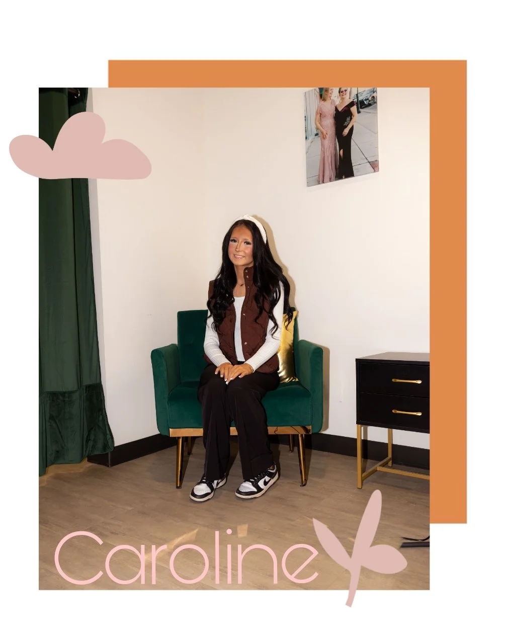 A young woman with long, dark hair sits on a green velvet chair in a room with a white wall. She is smiling and wearing a white long sleeve shirt, a brown vest, black pants, and sneakers. There is a framed photo of two women in dresses on the wall, a black nightstand with gold handles, a green curtain, and decorative pink clouds and butterfly graphics on the image. The name 'Caroline' is written at the bottom in pink letters.