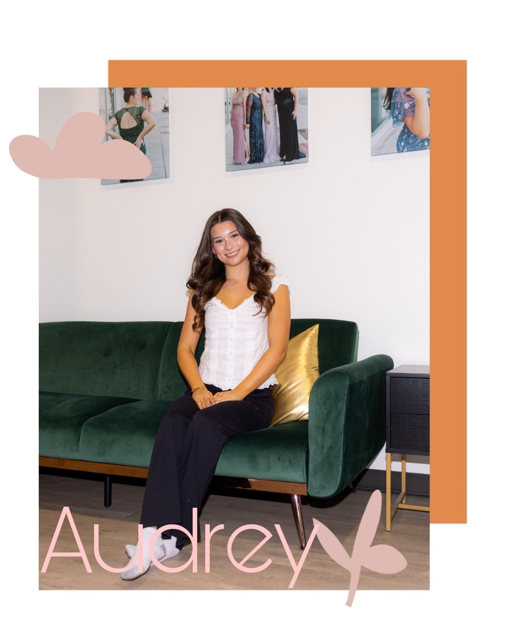 A young woman with long brown hair wearing a white top and black pants sitting on a green velvet sofa with a gold pillow, smiling at the camera. Behind her is a white wall with three photos in frames of women in dresses, and an orange and pink decorative border with the name "Audrey" in pink and a butterfly graphic.
