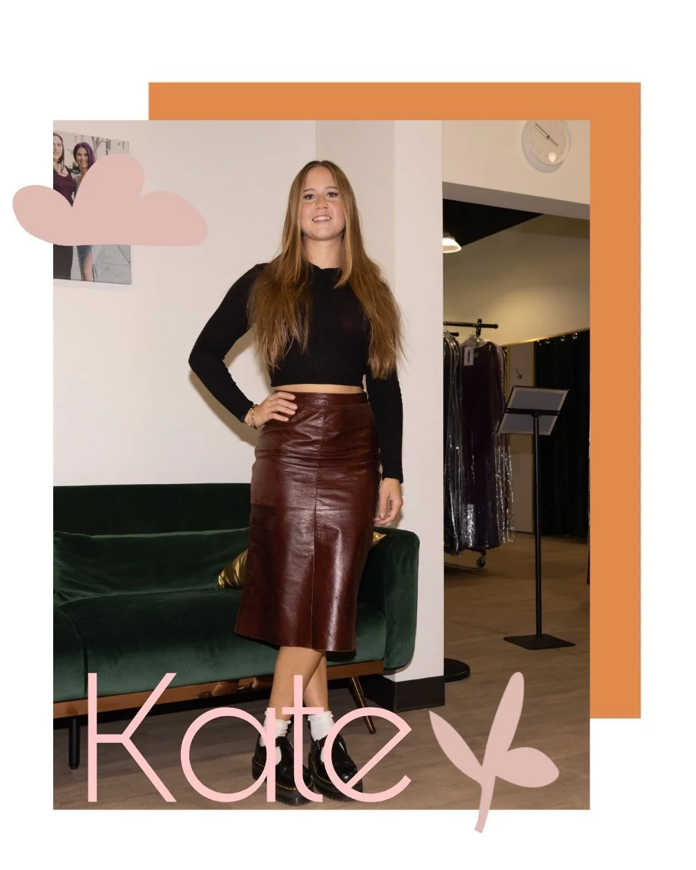 A young woman with long, straight hair, wearing a black long-sleeve top and a high-waisted leather skirt, standing with one hand on her hip inside a room with a green velvet couch and a clothing rack in the background. The word "Kate" is written at the bottom with a pink flower and cloud decoration.