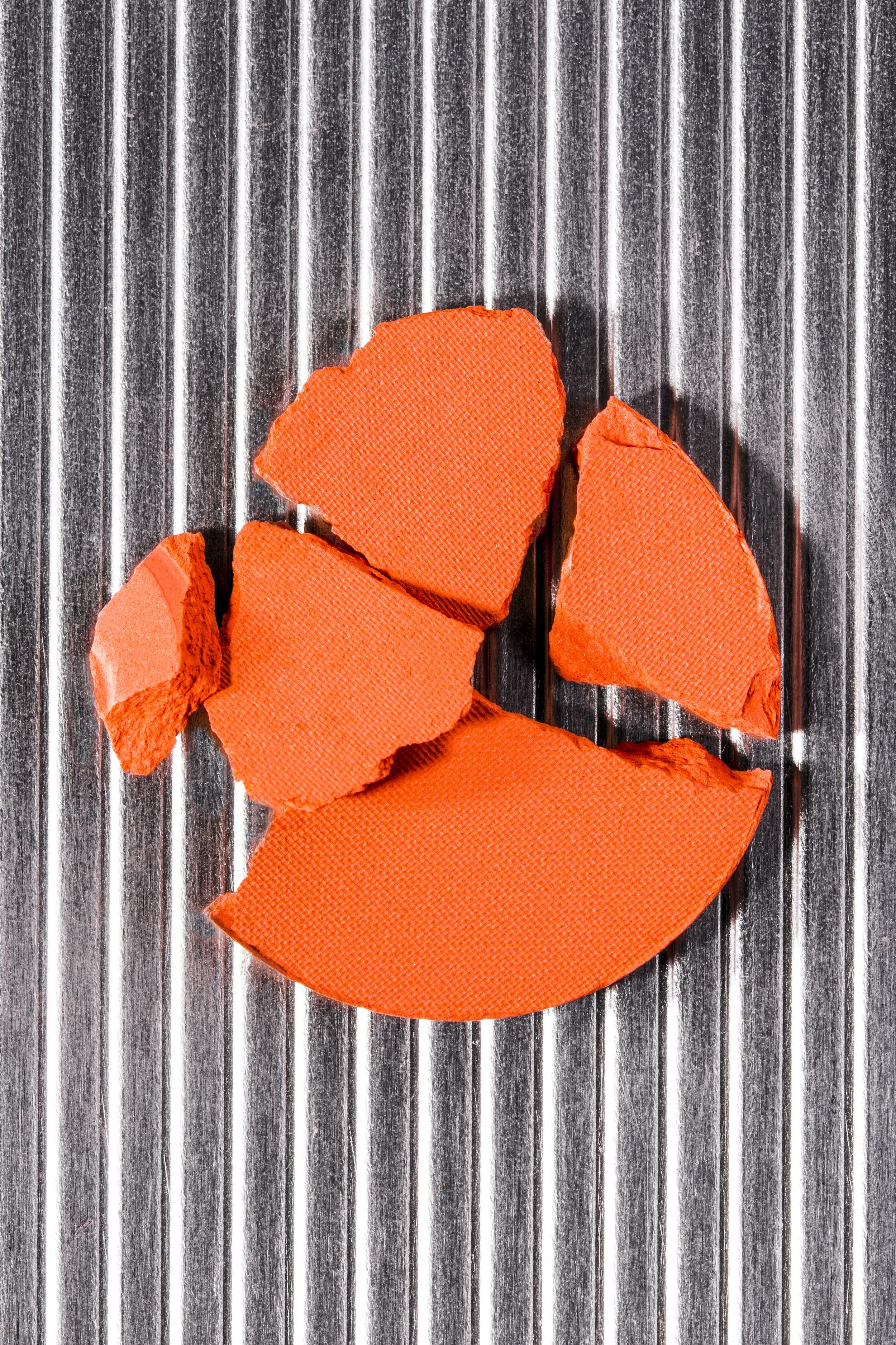 Rote Knetmasse in Form eines lachenden Smileys auf einer metallischen, gerillten Oberfläche.