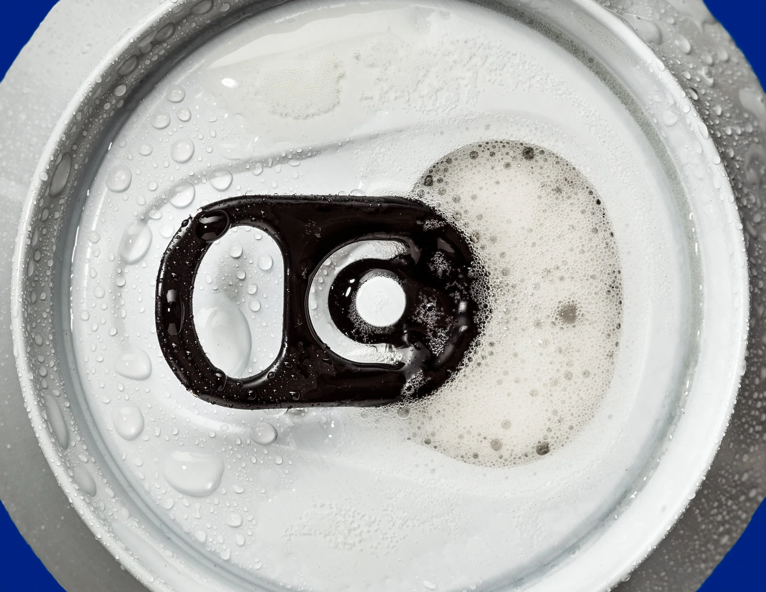 Nahaufnahme einer geöffneten Getränkedose mit Weißbier, Schwebeteilchen und Wassertröpfchen auf der Oberfläche.