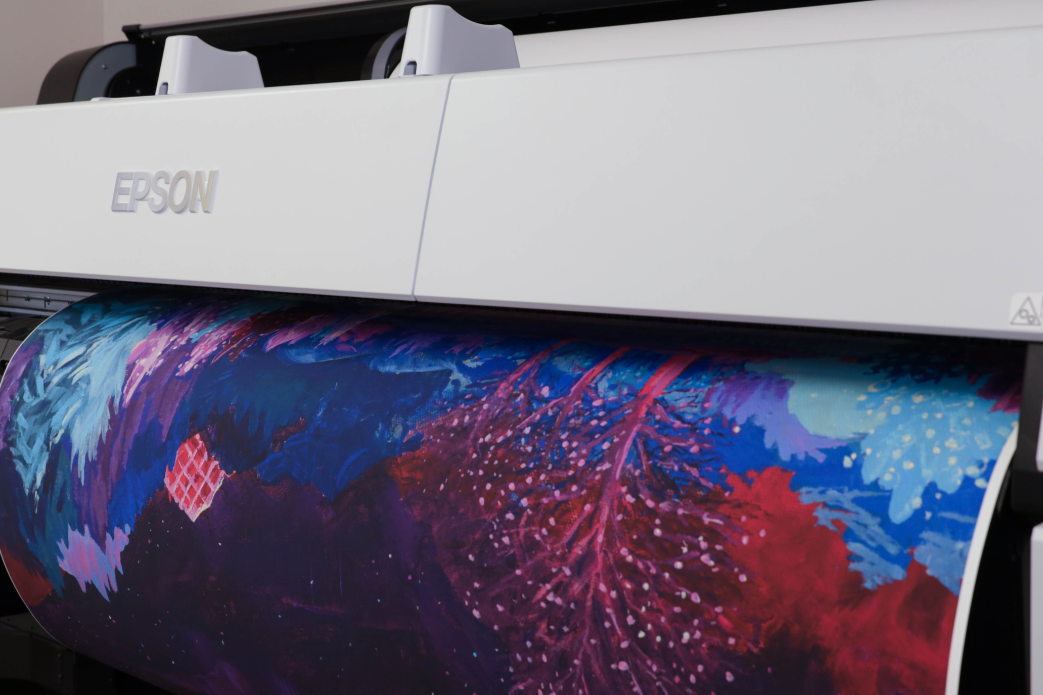 Close-up of an Epson wide-format printer printing a colorful, abstract artistic design with blue, red, purple, and pink hues.