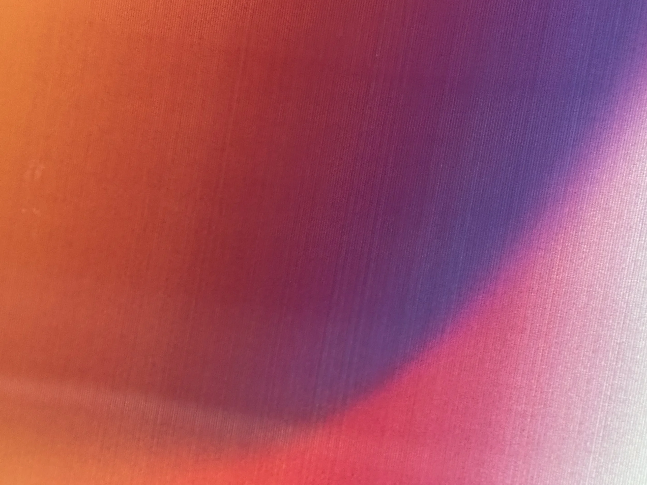 Close-up of a computer or phone screen with a lenticular gradient of warm colors like red, pink, purple, and orange.