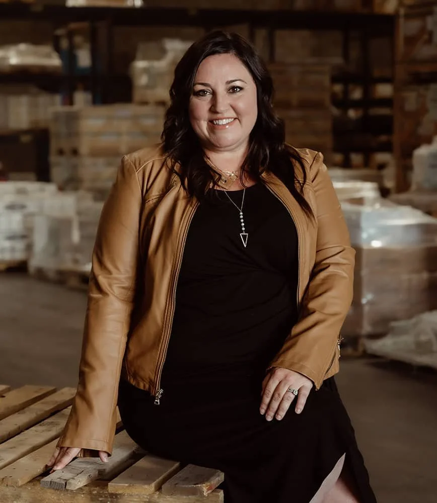 Interior designer and tile expert Sarah Shaid, smiling and posing in a warehouse.