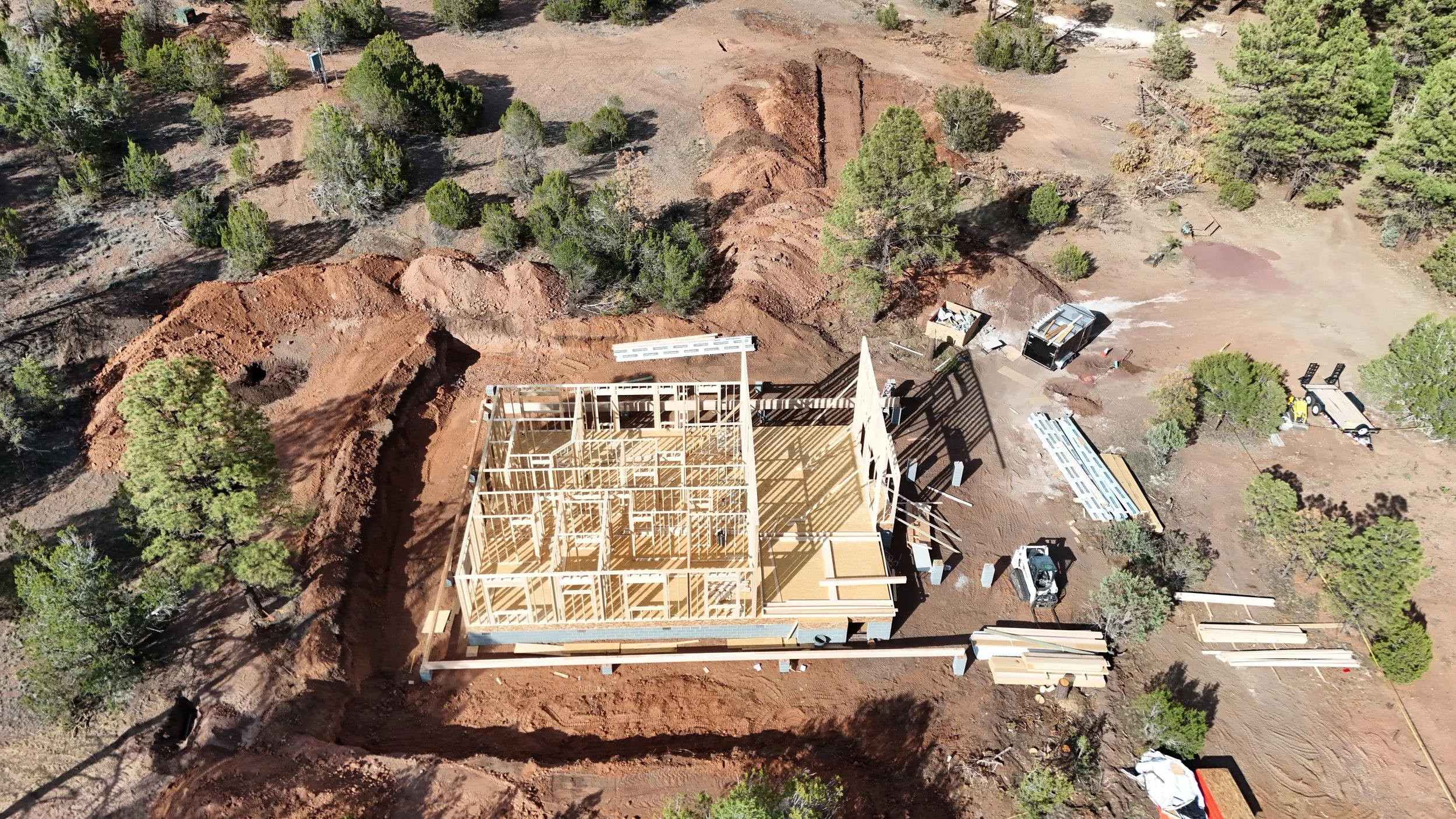 An aerial view of a residential house being built in Arizona. The build is in the house framing phase.