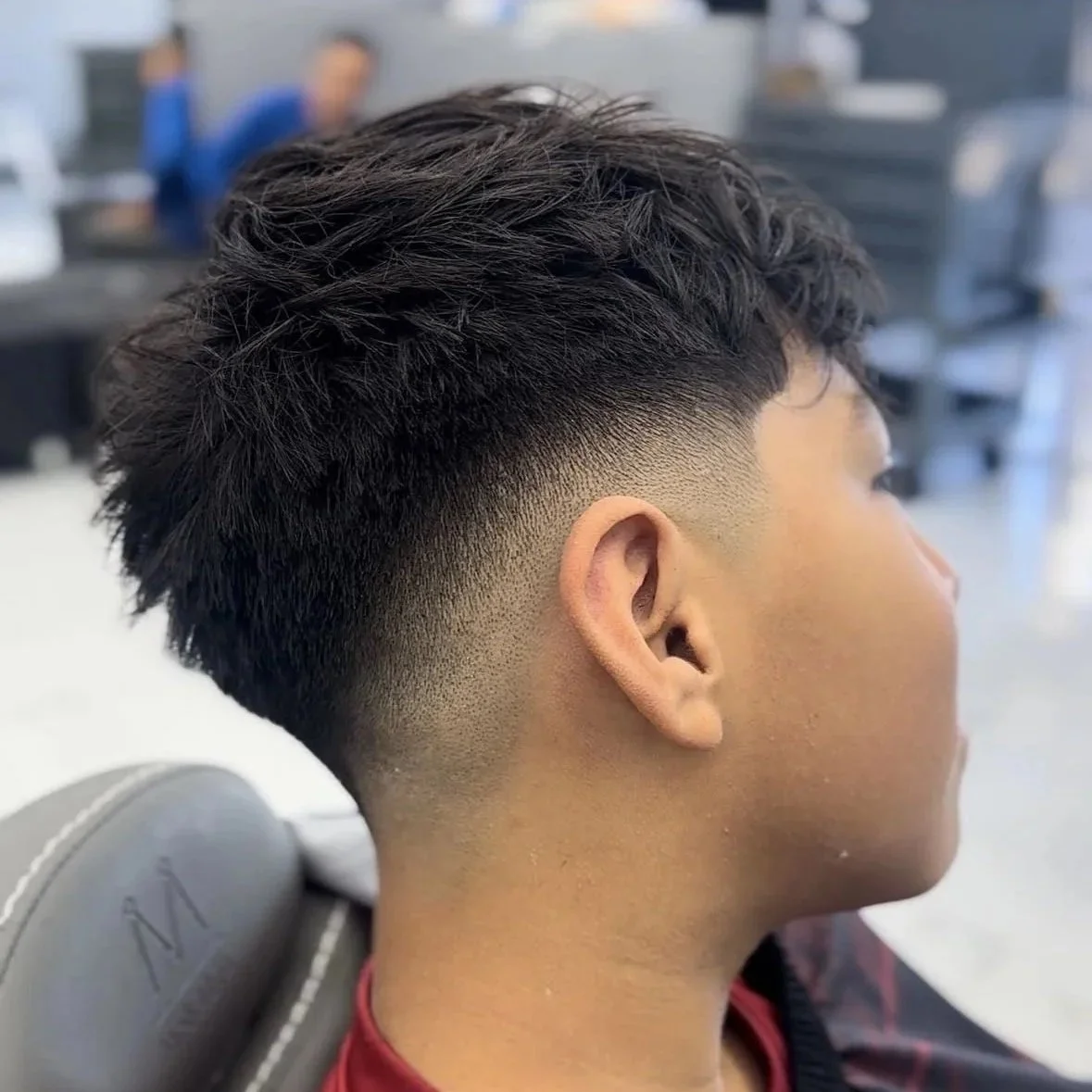 Side view of a young man with a modern fade haircut in a barber shop.
