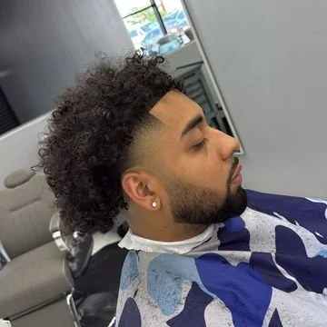 Young man with curly hairstyle getting a haircut in a salon.