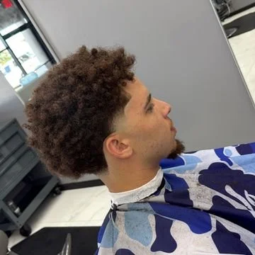 Young man with curly hair getting a haircut in a salon