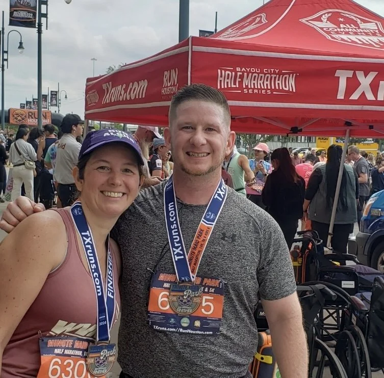 Coach Nicole and runner at the end of a half marathon, smiling, wearing finisher medals
