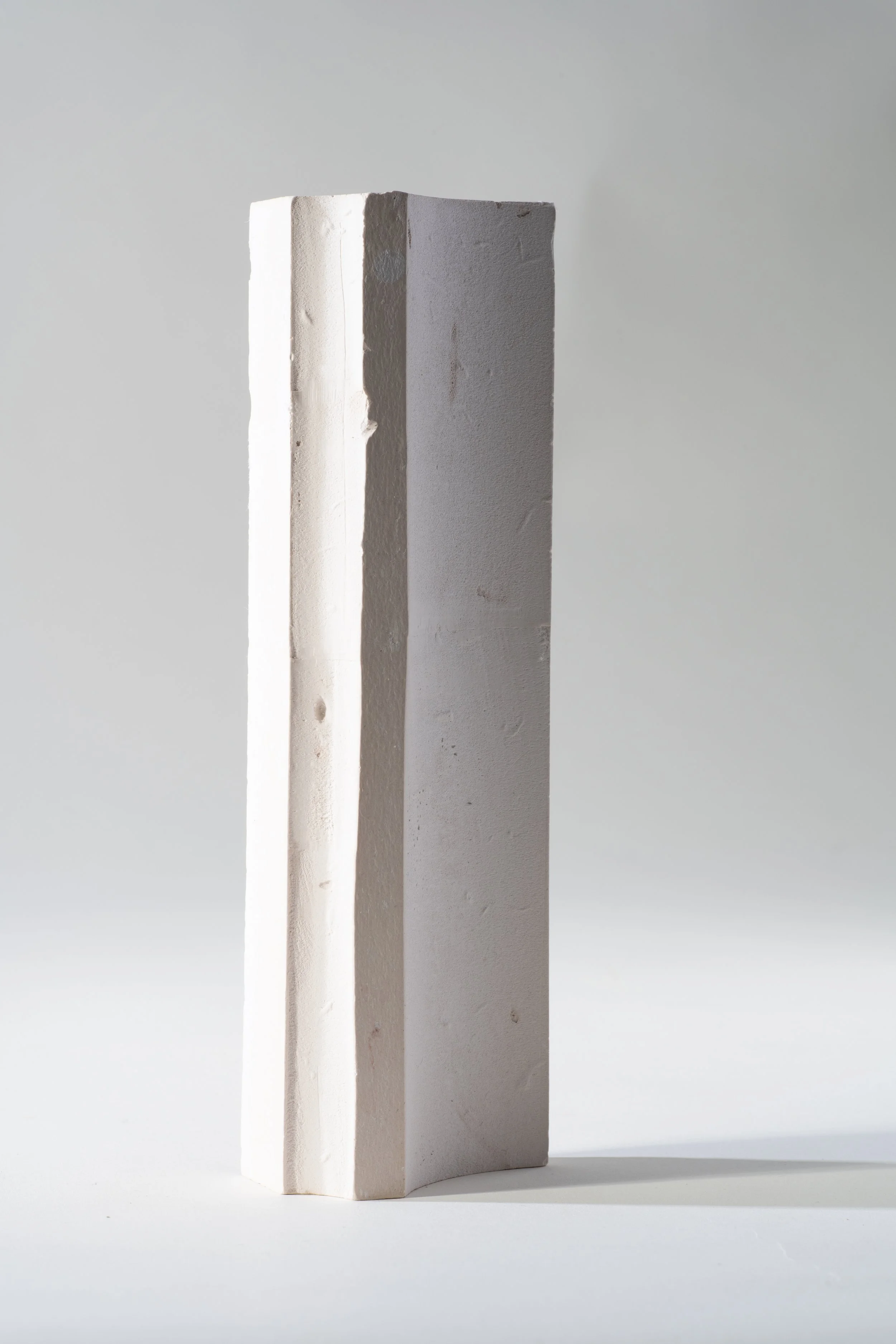 A vertical, white, rectangular brick standing upright on a plain, light background.