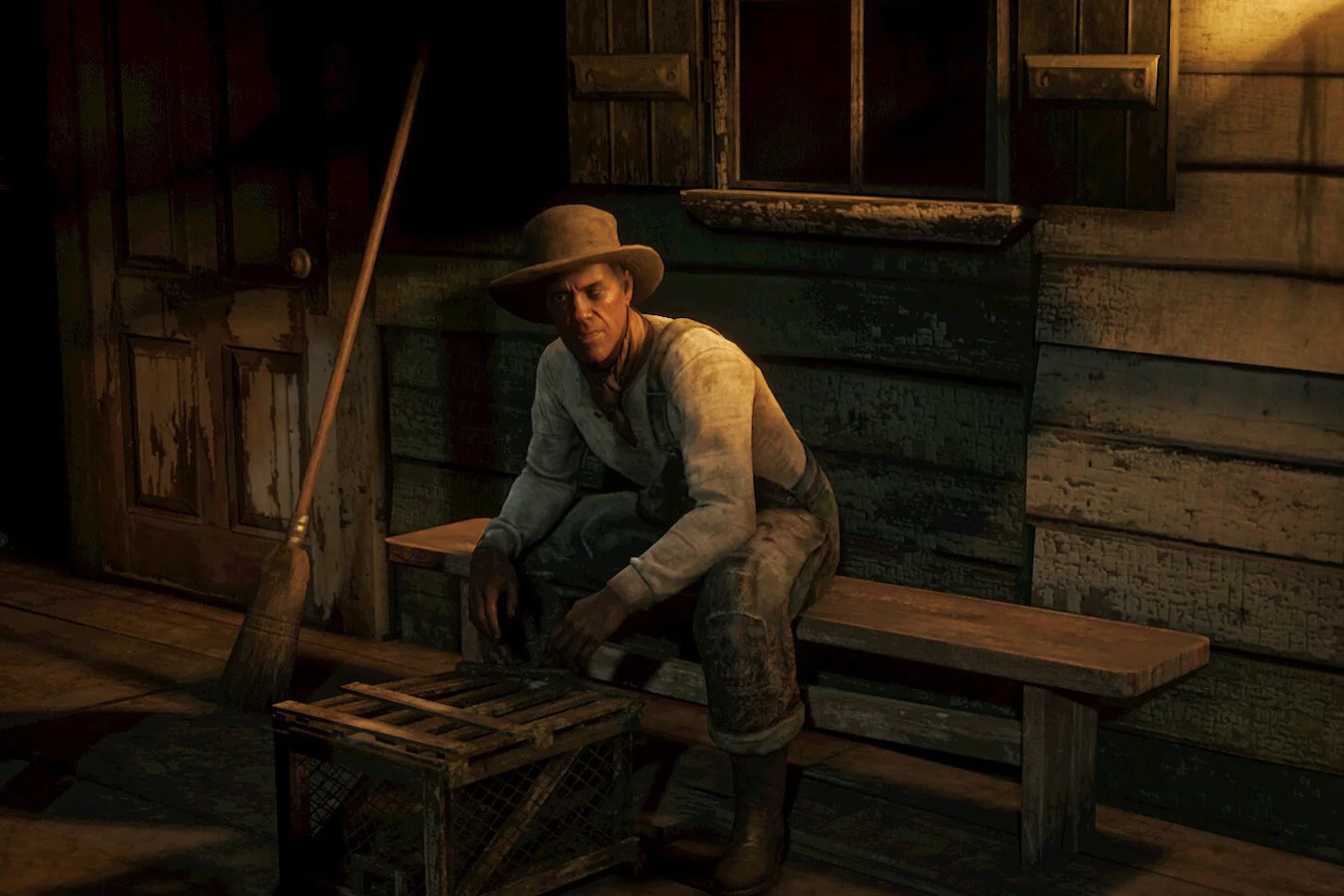 A man dressed as a cowboy sitting on a wooden bench inside a rustic cabin with wooden walls, wearing a wide-brimmed hat and old-fashioned clothing. A broom and a wooden crate are positioned next to him.