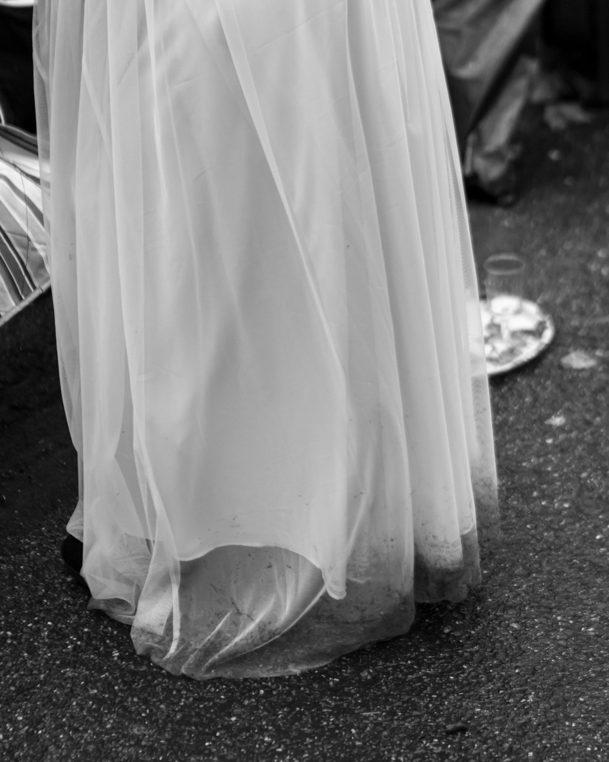 A white flowing dress or fabric draped over an object on a rough outdoor surface.