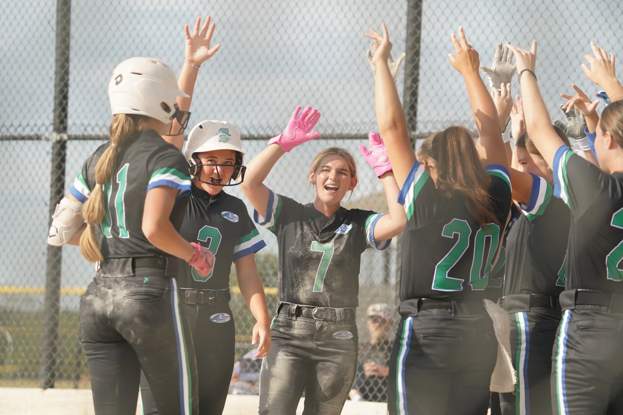 Girls' softball team celebrating together on the field