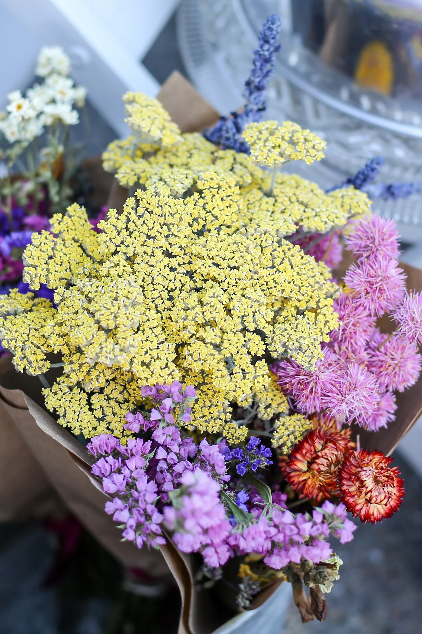Colorful bouquet of yellow, purple, pink, and orange flowers arranged in a paper wrapper.