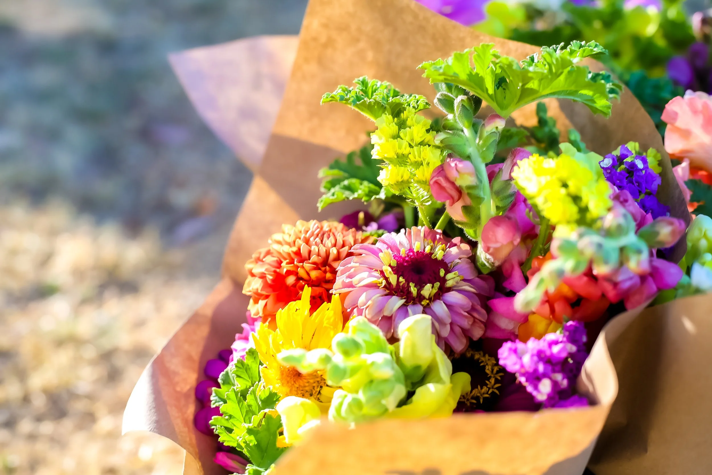 Colorful bouquet of various flowers wrapped in brown paper.