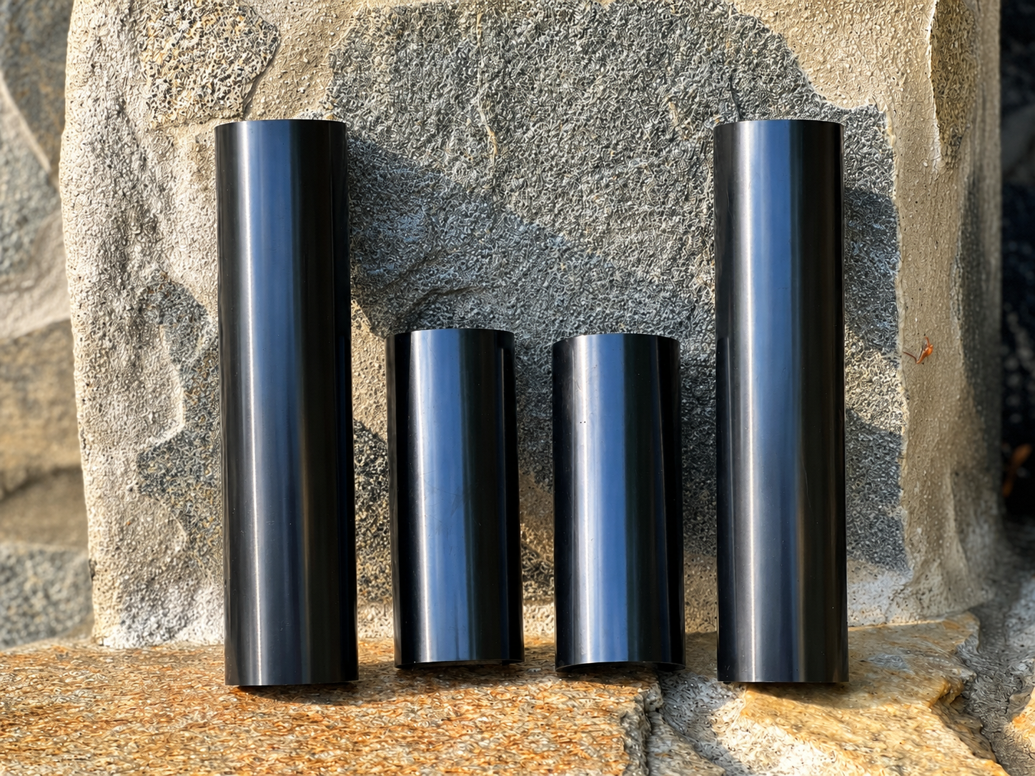 RokPro four-piece dirt bike fork guard set with two 6-inch and two 10-inch guards. arranged vertically on a rocky surface